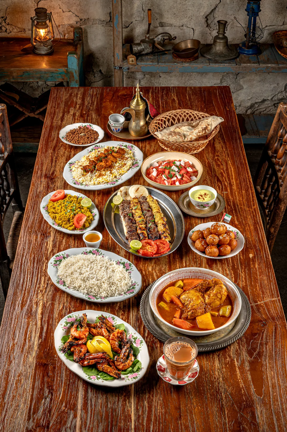 A long wooden table set with Emirati dishes, seen from above