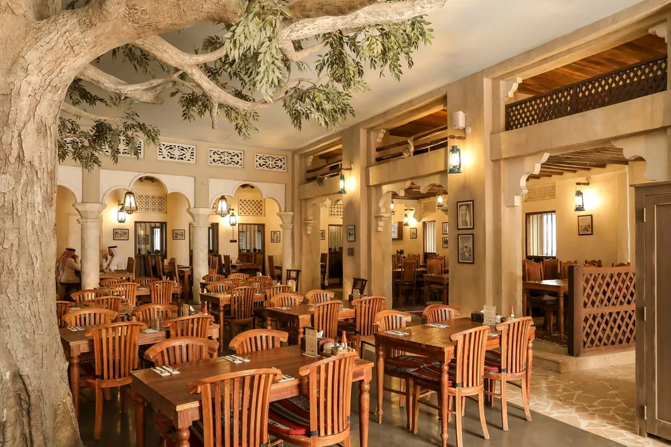 An Al Fanar dining room built around a large tree feature, with lanterns and wooden chairs